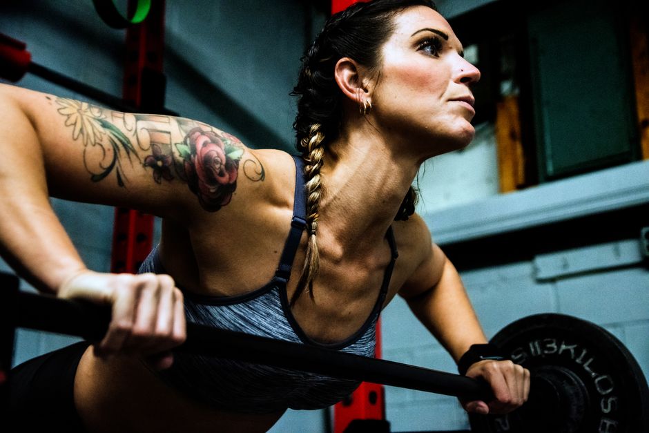 A fit woman lifting a barbell in a dimly lit gym, showcasing strength and determination.