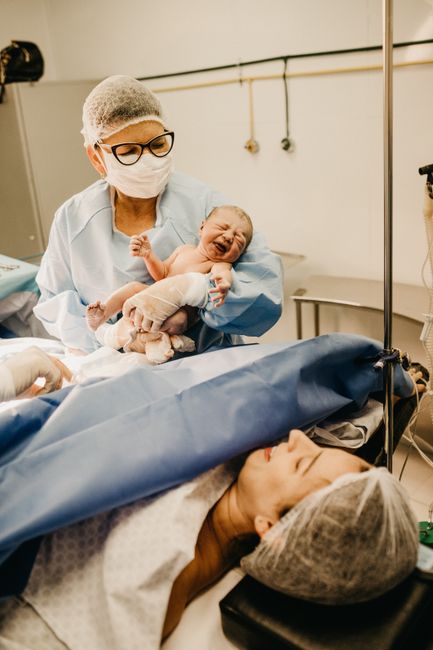 Mother gently holding newborn baby in hospital setting, showcasing warmth and love.