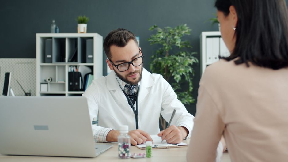 Doctor in white coat consulting patient in a modern office setting.